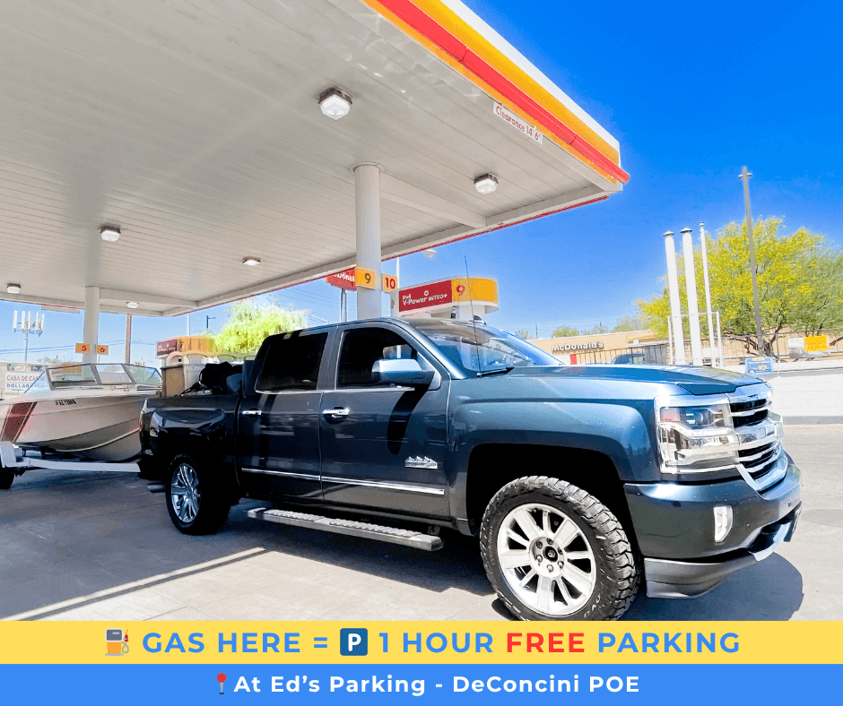 Black pickup truck towing a boat at a gas station offering one hour free parking.